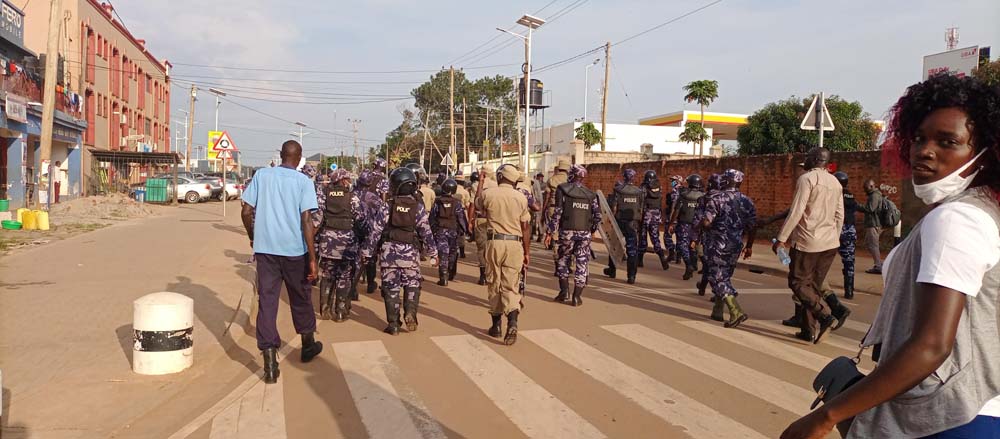 A female journalist joins her colleagues in covering a demonstration controlled by police in Gulu City